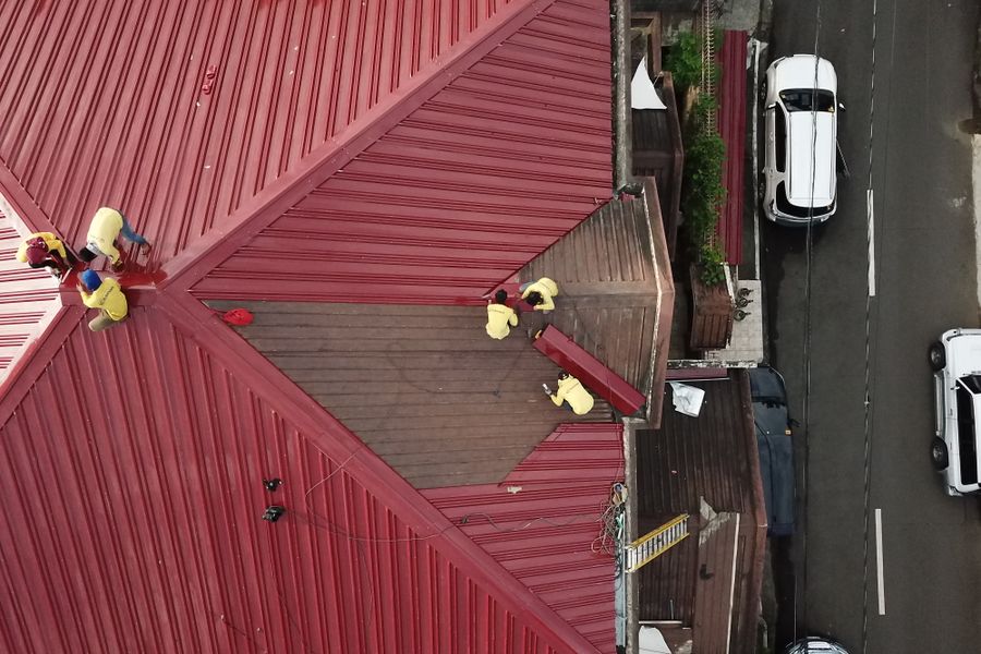 Roofers repairing a red metal roof